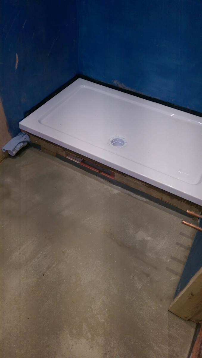 During — shower tray positioned on its timber frame with copper pipework underneath